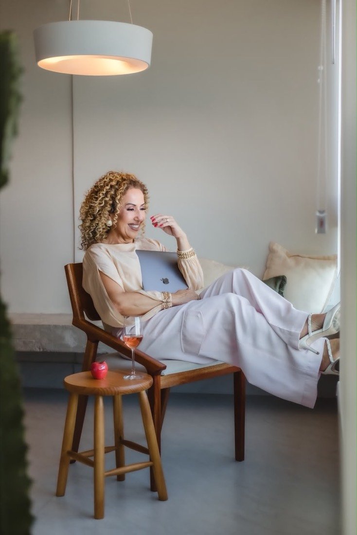 Flávia sentada em poltrona, em ambiente de trabalho